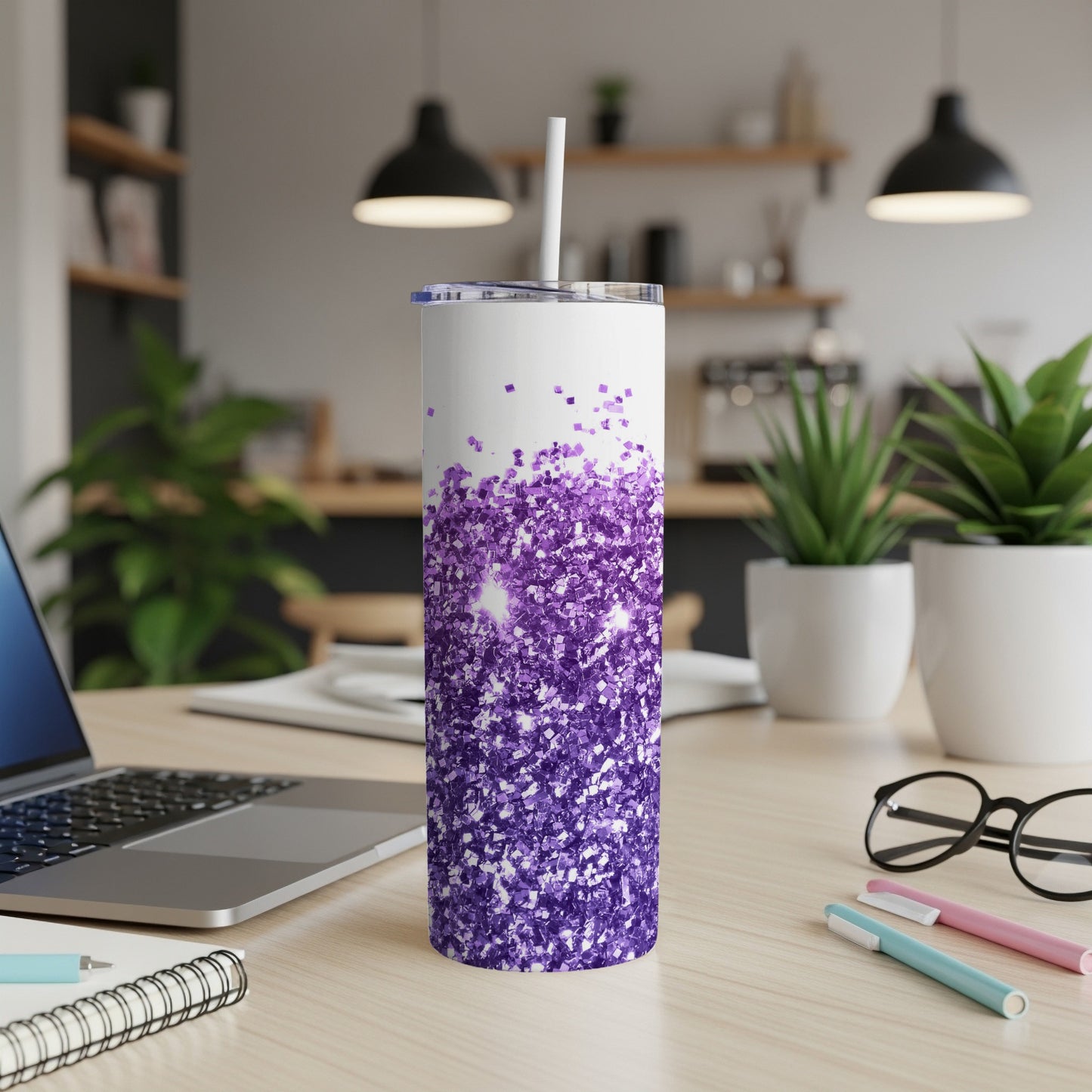 White tumbler with purple glitter design and straw on desk.