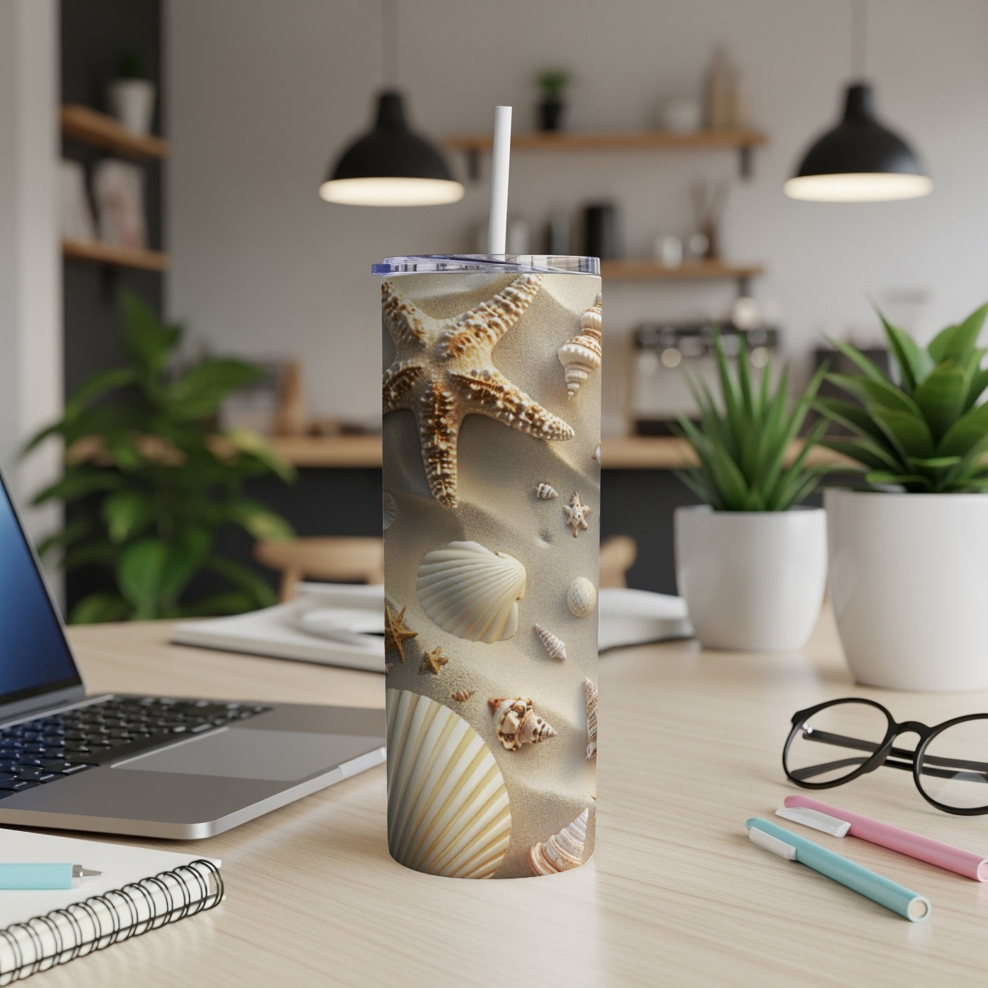 Beach-themed tumbler with seashells and sand, on a desk.