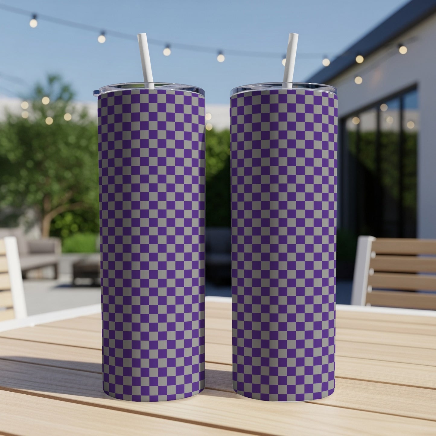 Two purple and gray checkered tumblers with straws on a wooden table.