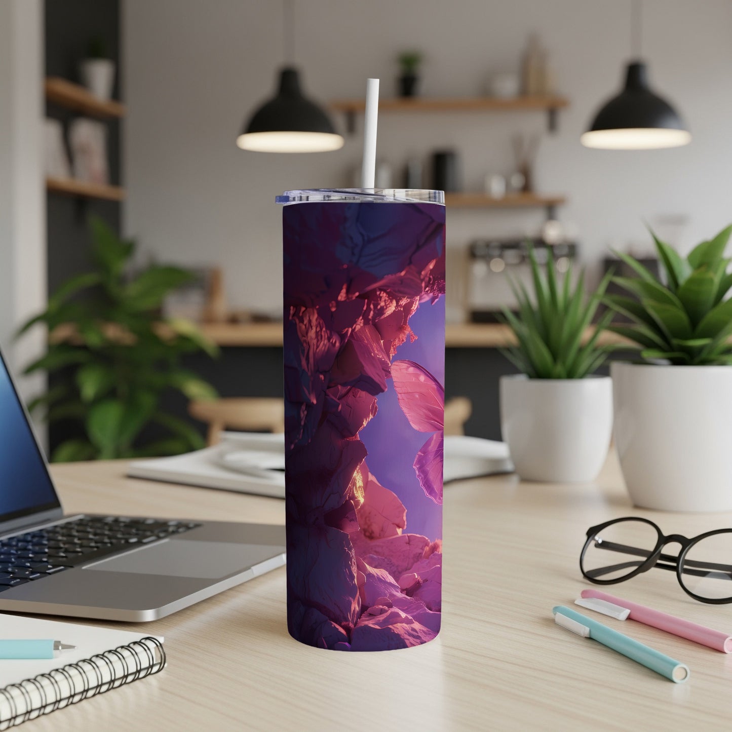 Purple and pink abstract mountain landscape tumbler with straw on desk.