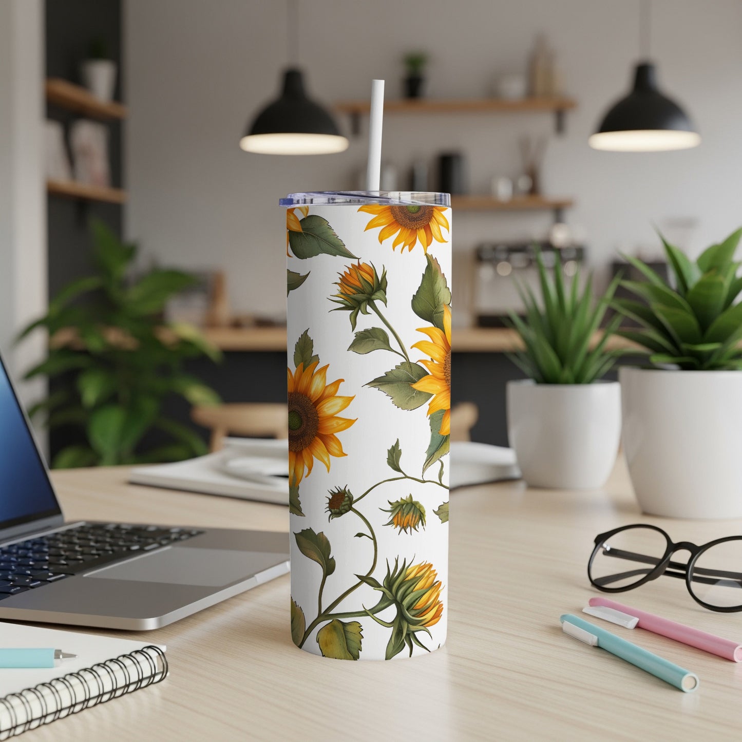 White tumbler with sunflowers and green vines, on a desk.