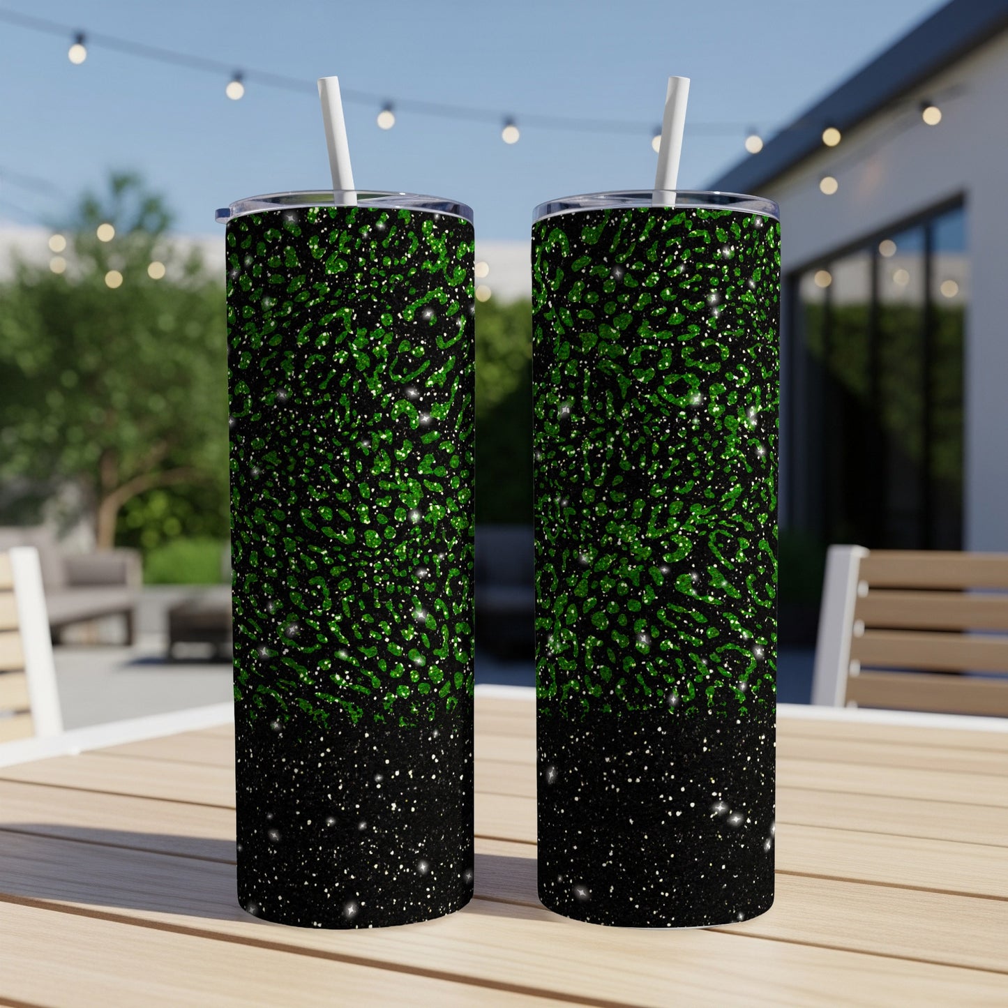 Two green and black glitter speckled tumblers with straws on a table.