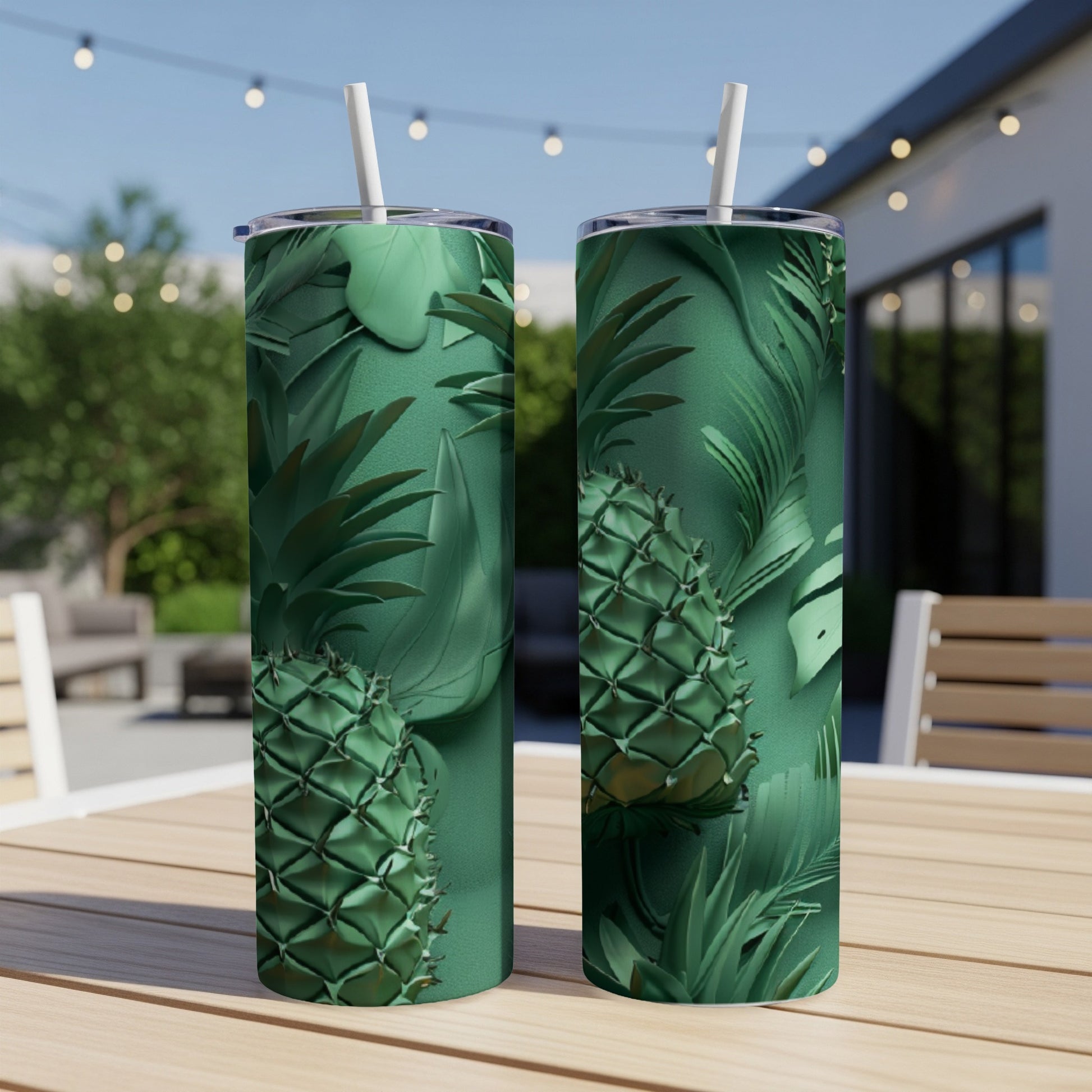 Two green tumblers with pineapple and tropical leaf patterns on a patio table.