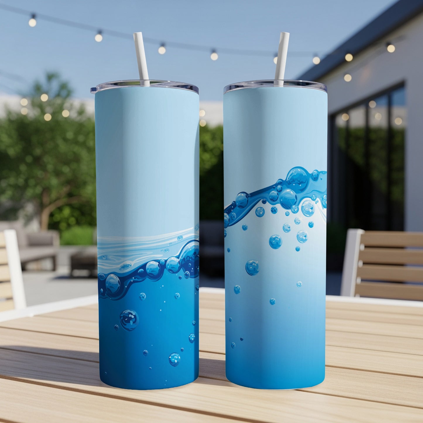 Two blue tumblers with bubbly water design on an outdoor table.