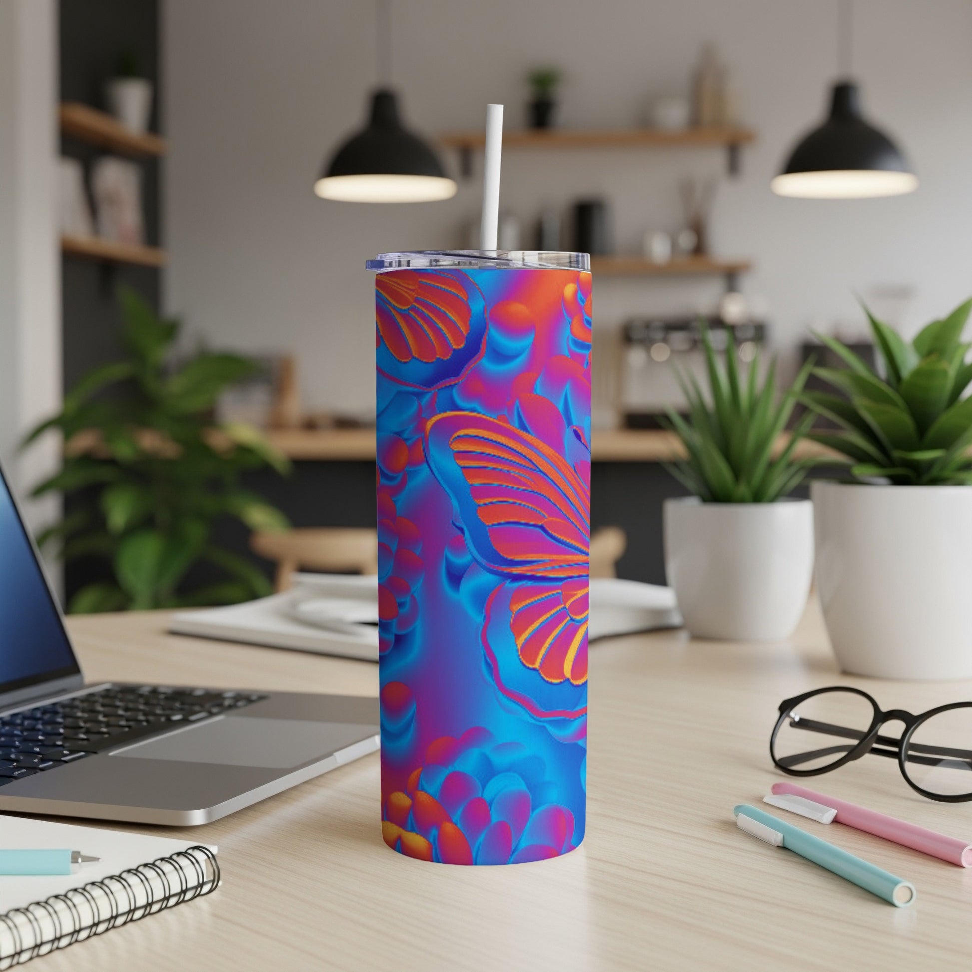 Tumbler with vibrant butterfly and floral pattern, on a desk.