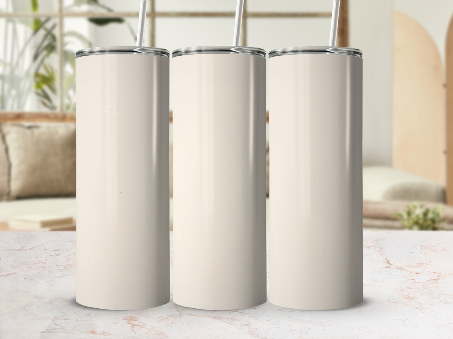 Three blank cream-colored tumblers with straws stand in a row.
