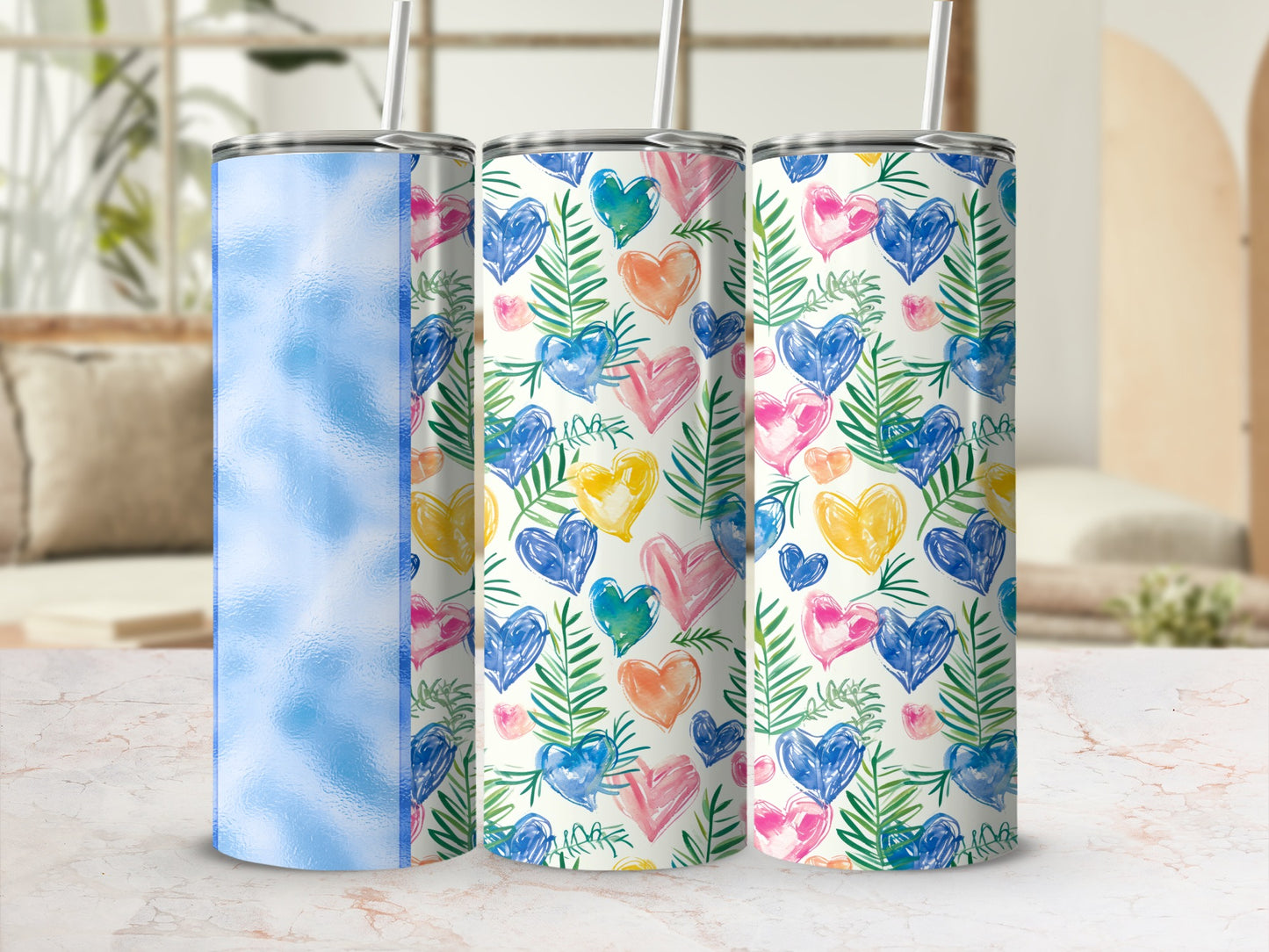 Three tumblers with heart and leaf patterns on a marble surface.
