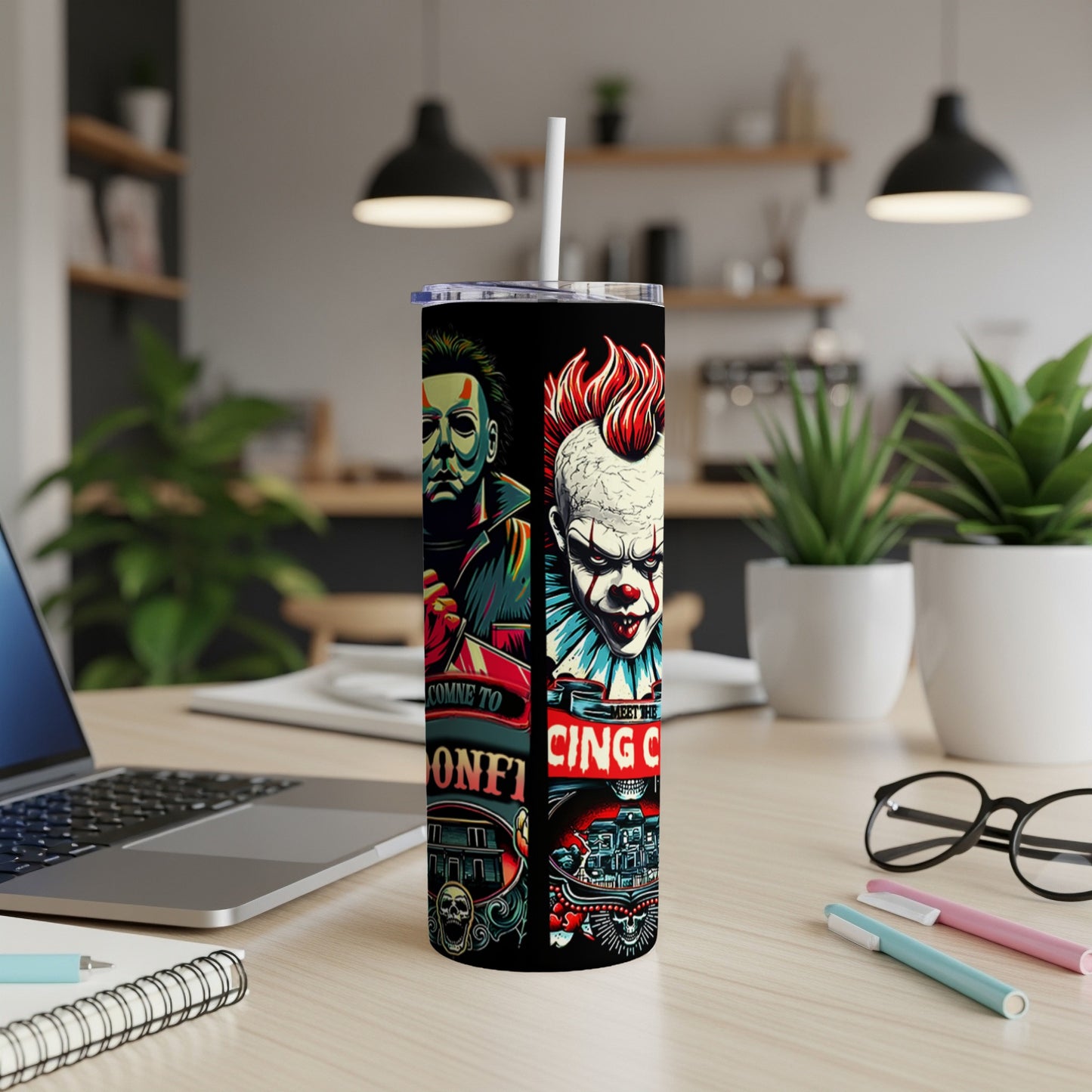 Tumbler with horror characters Michael Myers and Pennywise, on a desk.