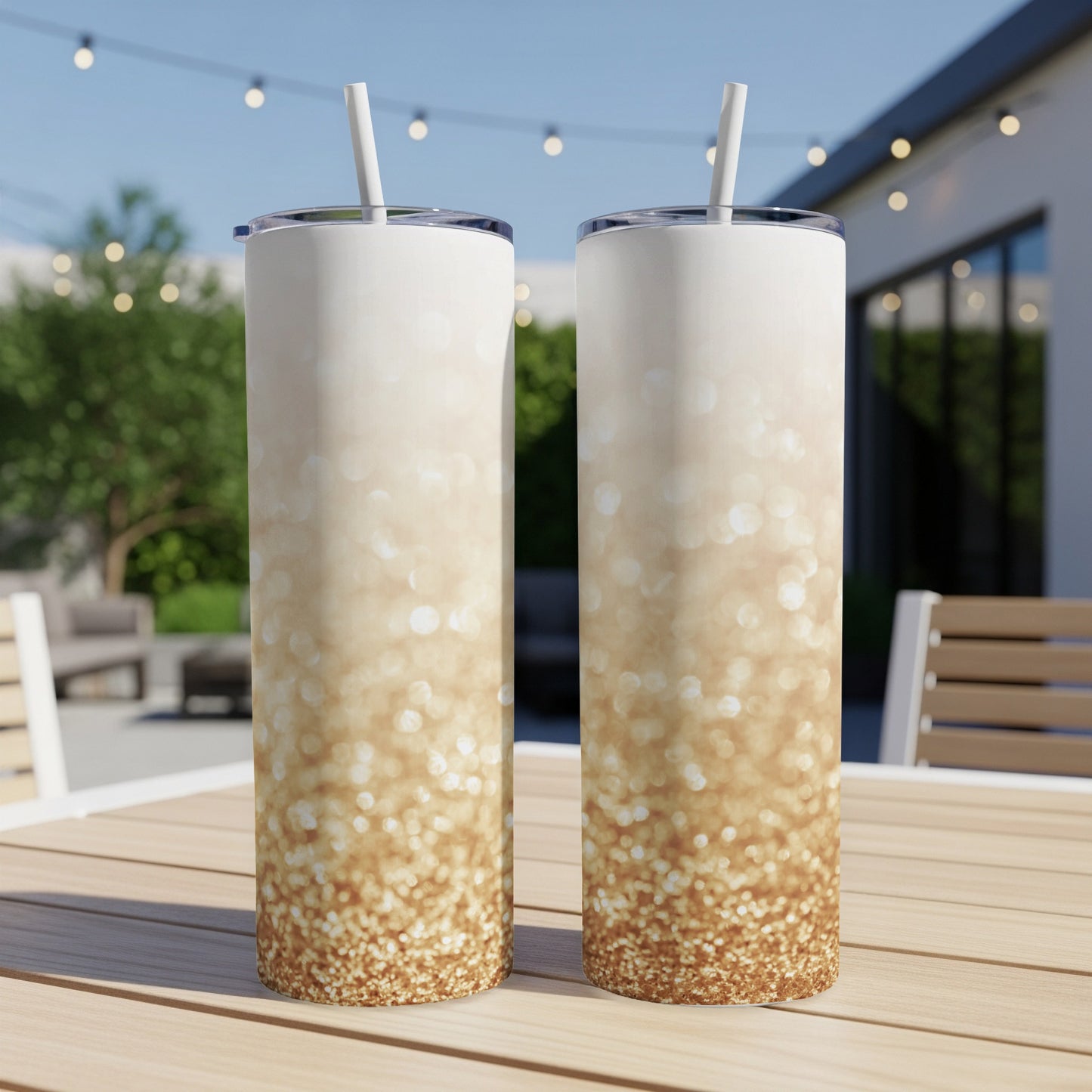 Two tall tumblers with a gradient of gold glitter, on a wooden table.