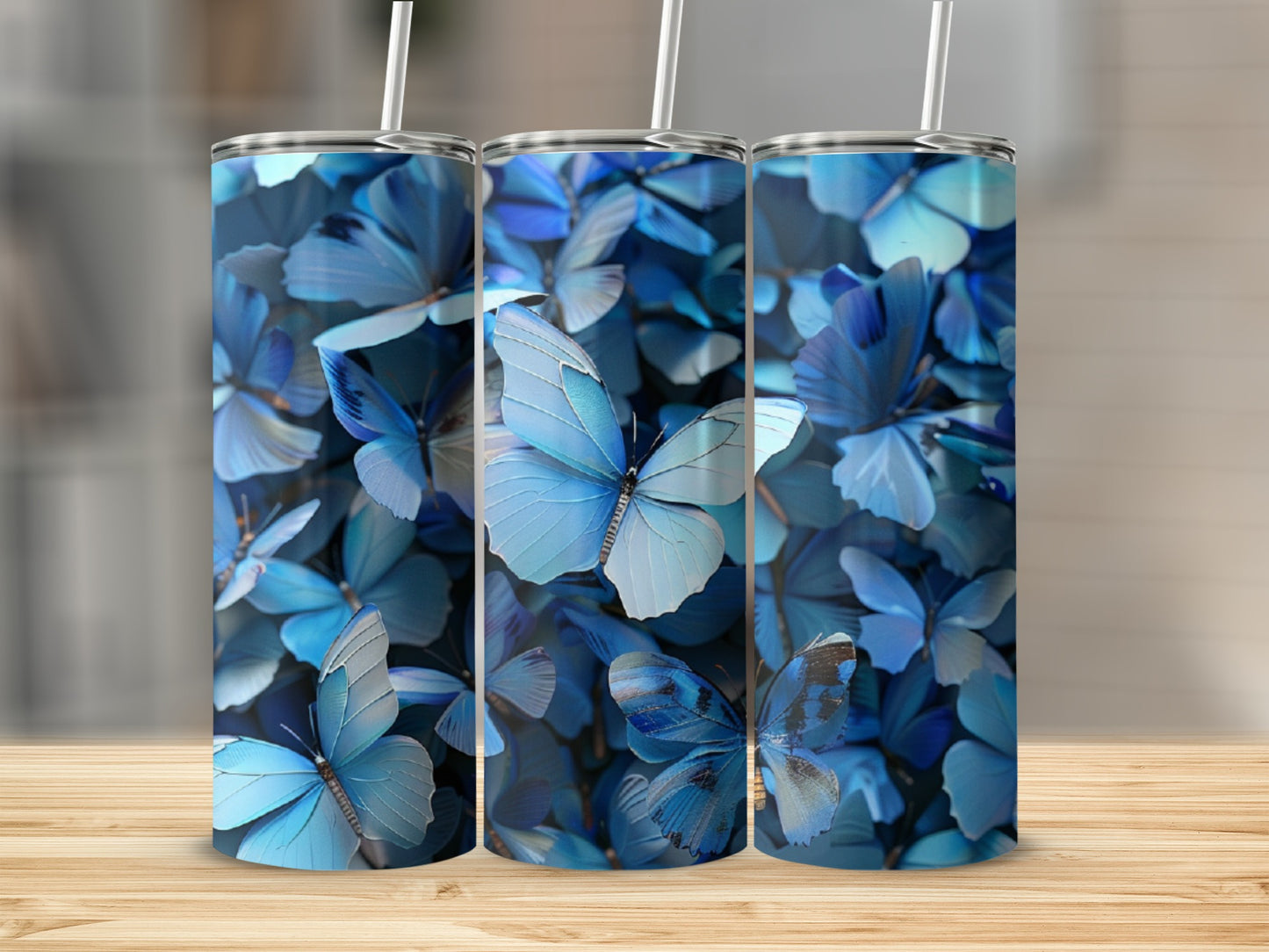 Three tall tumblers with a blue butterfly pattern on a wooden surface.