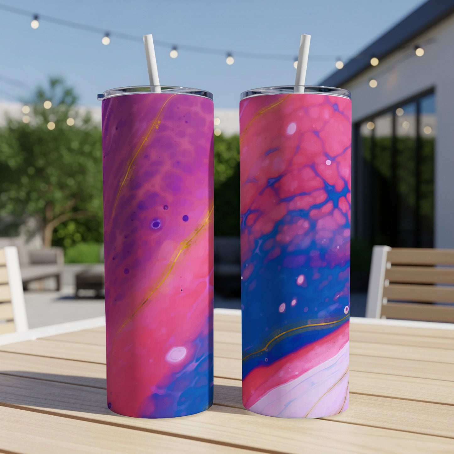 Two tumblers with abstract pink, blue, and gold marbled designs on a table.