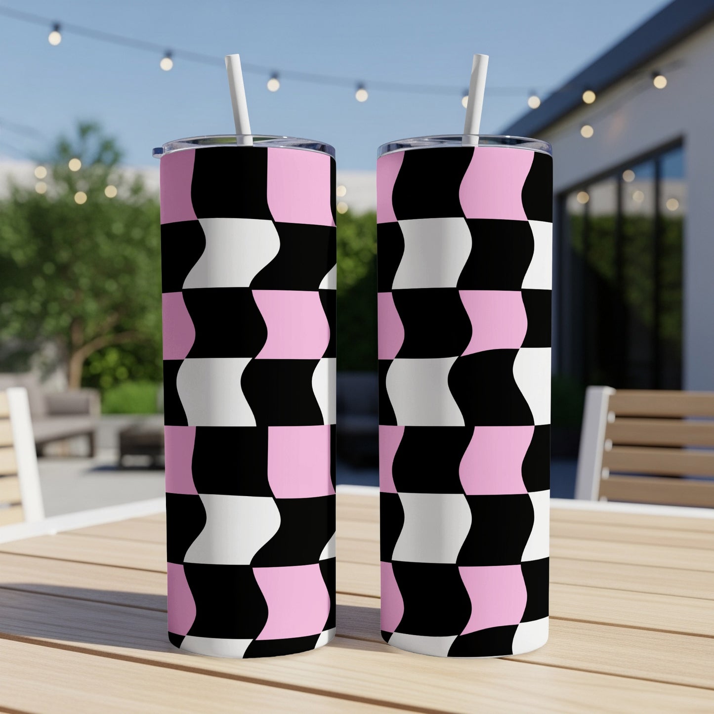 Two tall tumblers with a black, white, and pink checkerboard pattern sit on a table.