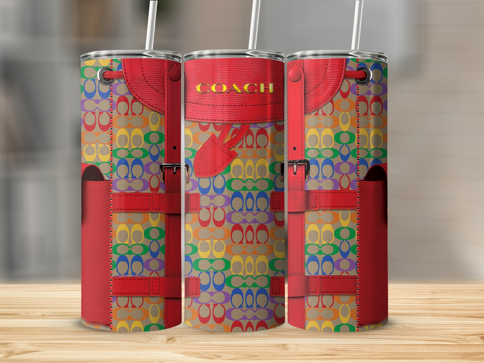 Three Coach tumblers with multicolor rainbow logo pattern and red leather accents.