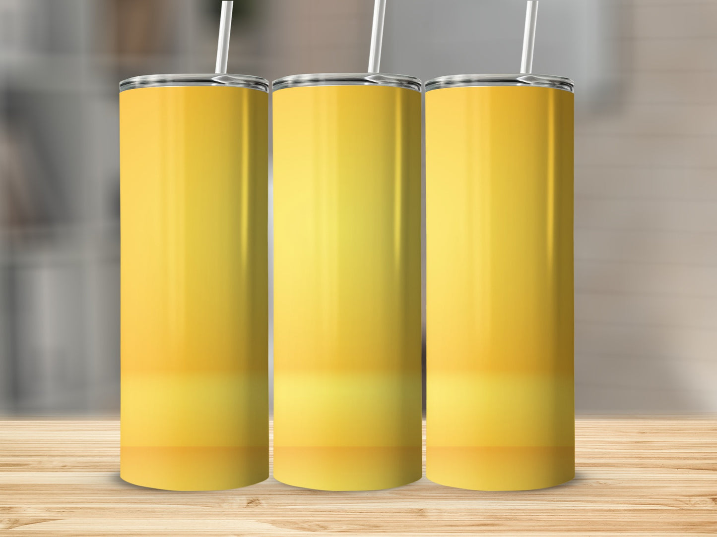 Three blank yellow gradient tumblers with straws on a wooden surface.
