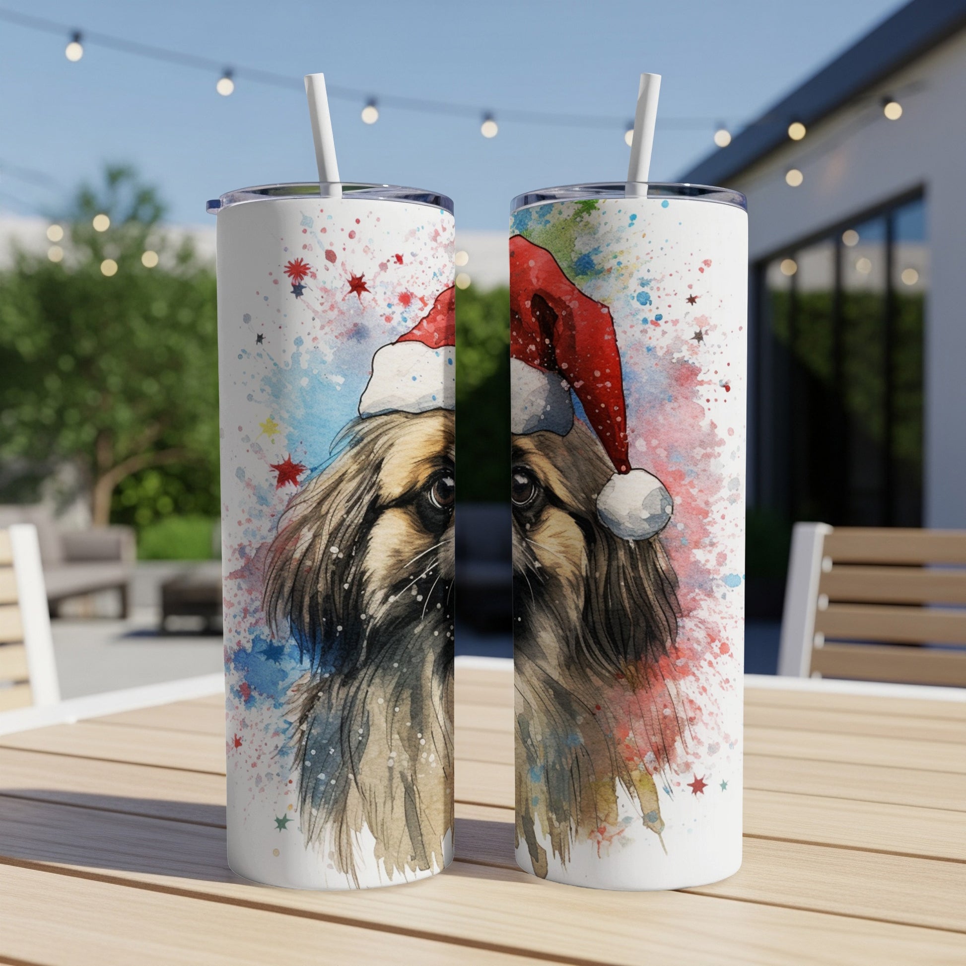 Two Santa hat-wearing dog tumblers with watercolor splashes on a patio table.