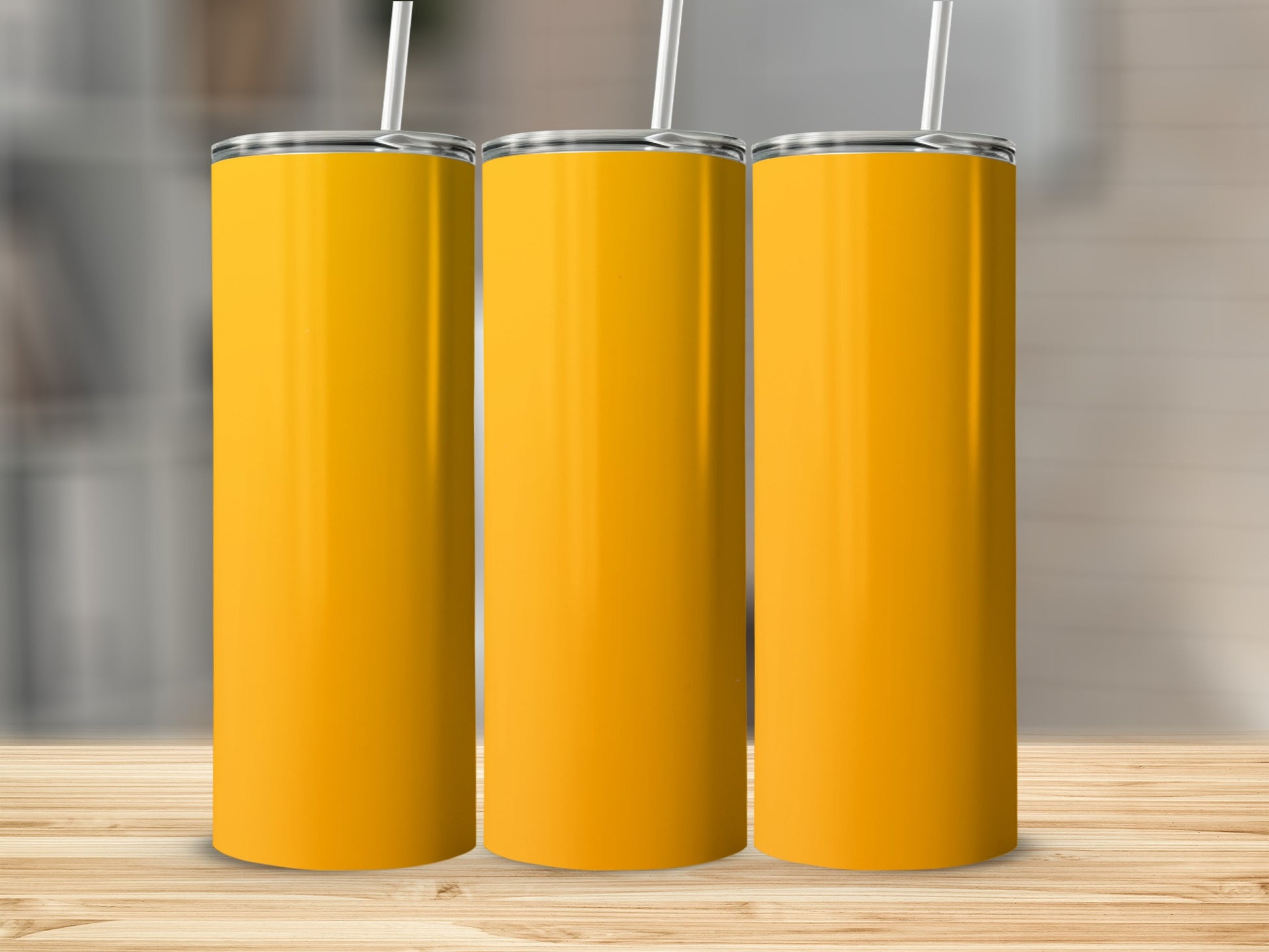 Three tall, yellow tumblers with white straws on a wooden surface.