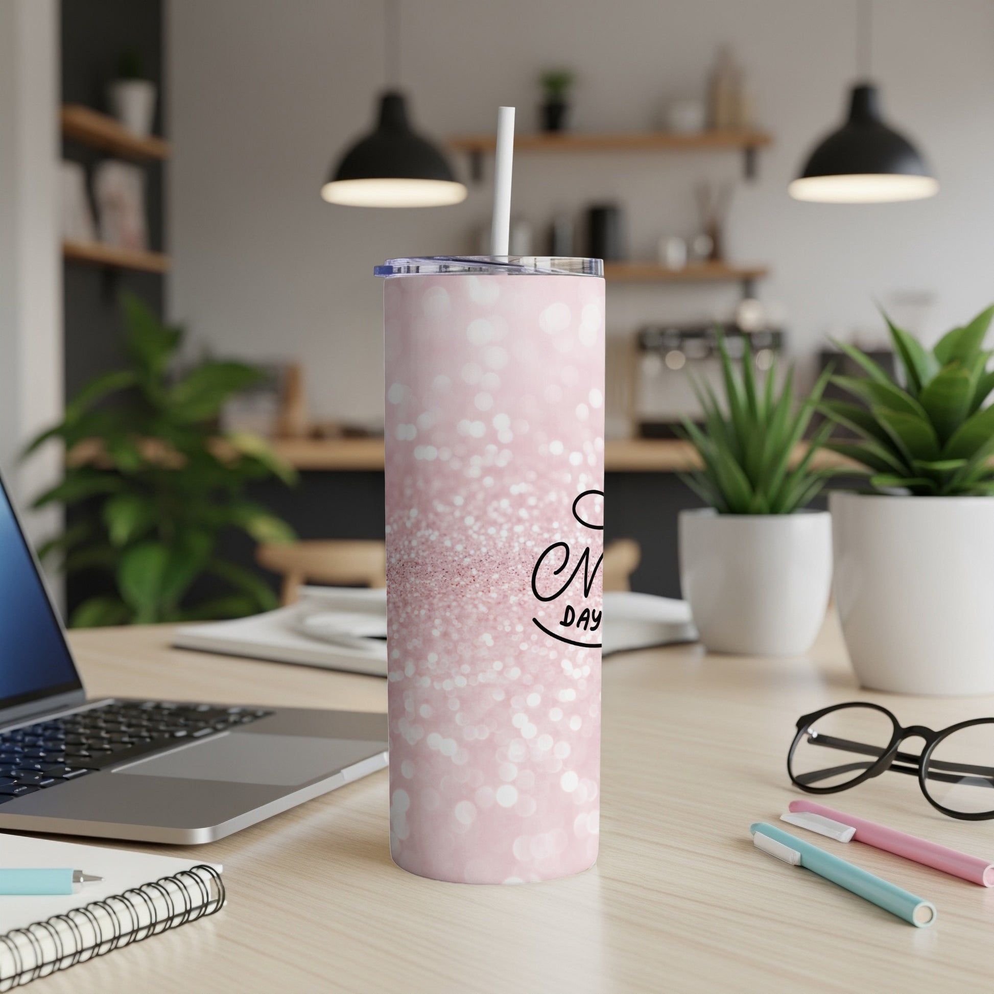 Pink glitter tumbler with "Mom" text and straw on desk.