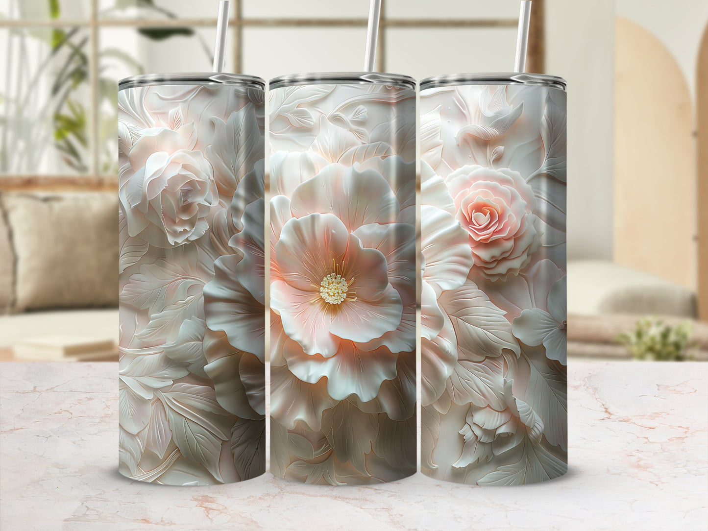 Three white and pink floral tumblers with straws on a marble countertop.