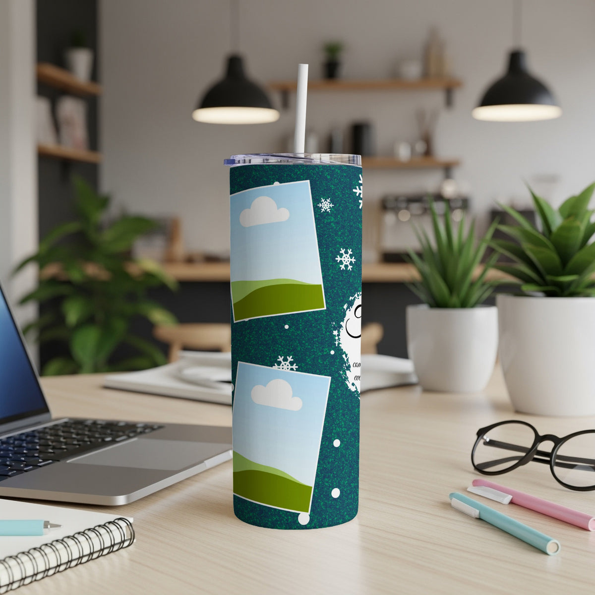 Dark teal tumbler with snowflakes and photo frames on a desk.