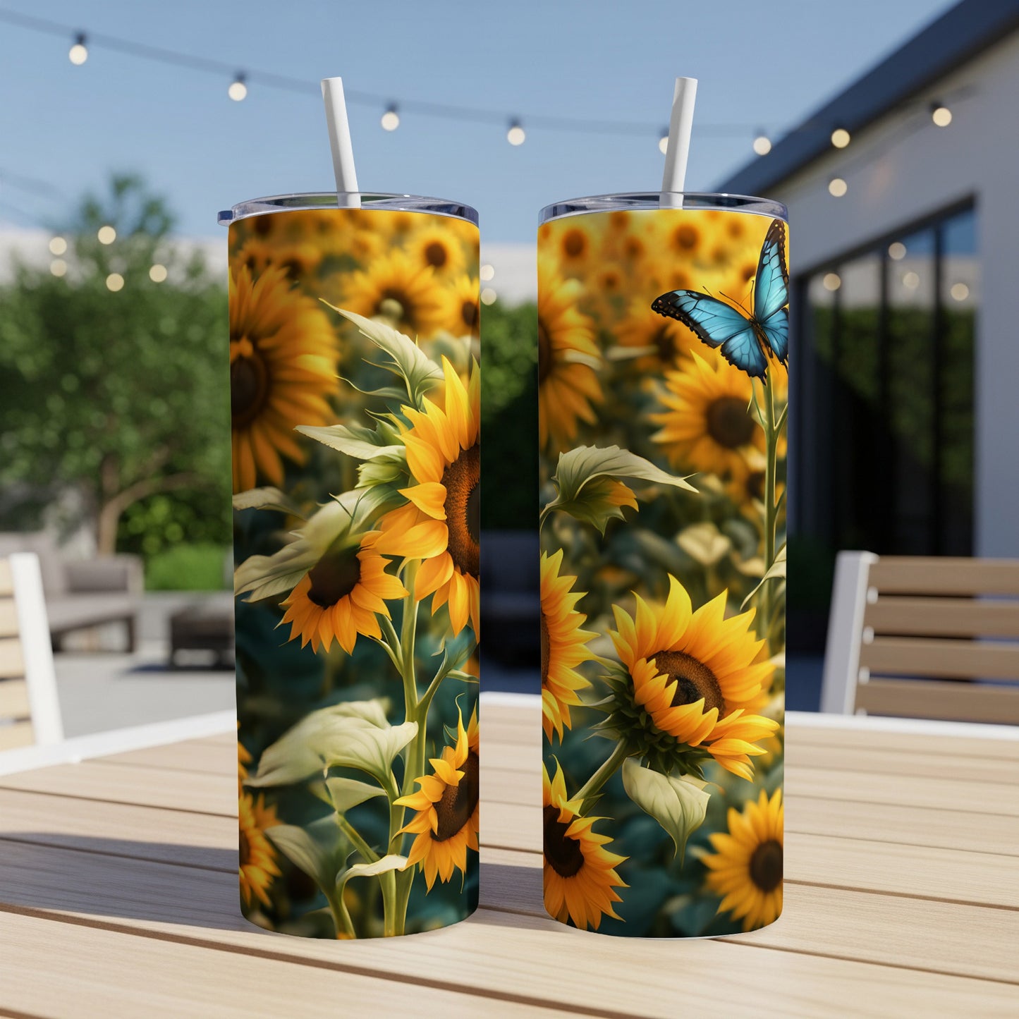 Two tumblers with sunflowers and a blue butterfly on a patio table.