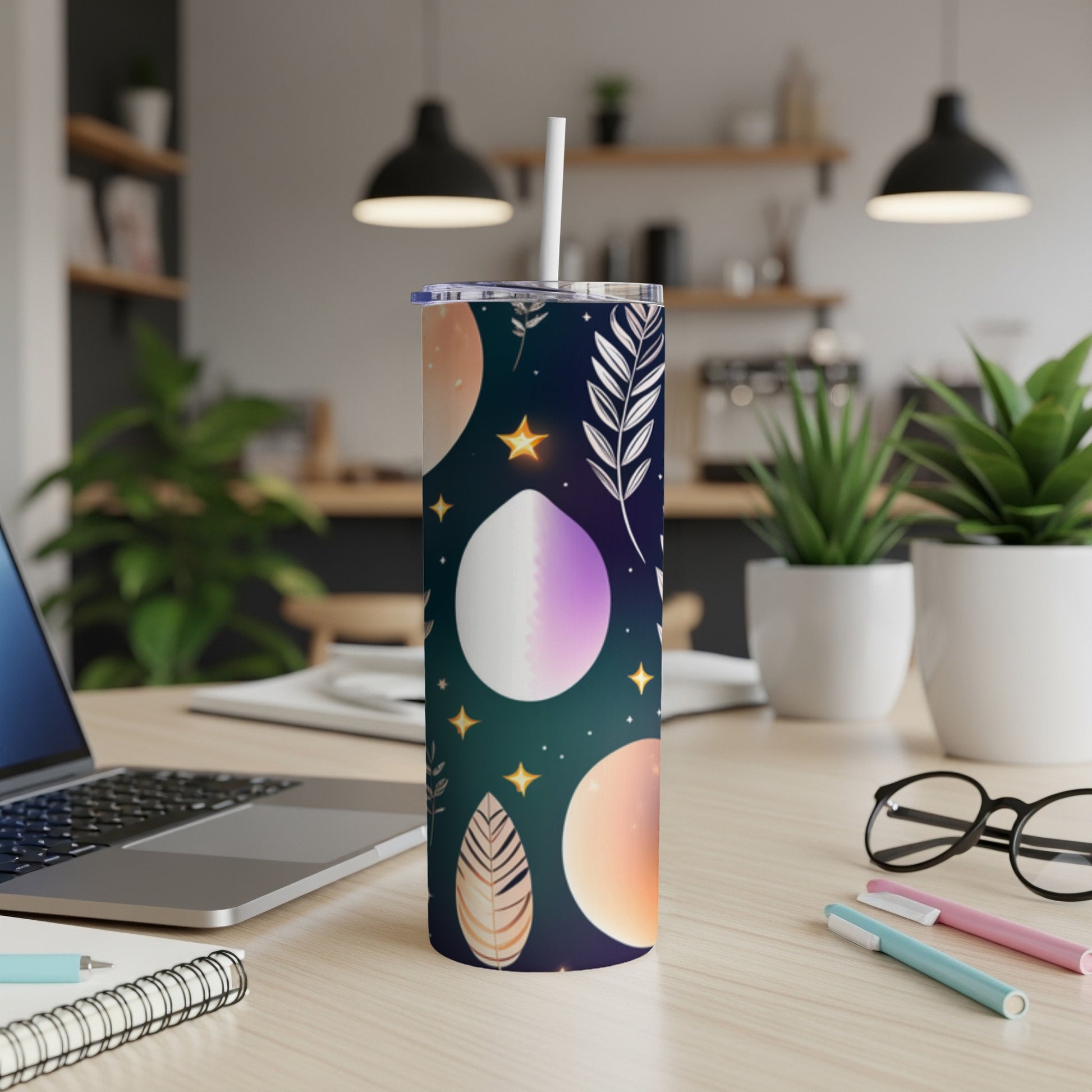 Tall tumbler with celestial print and straw on a desk.