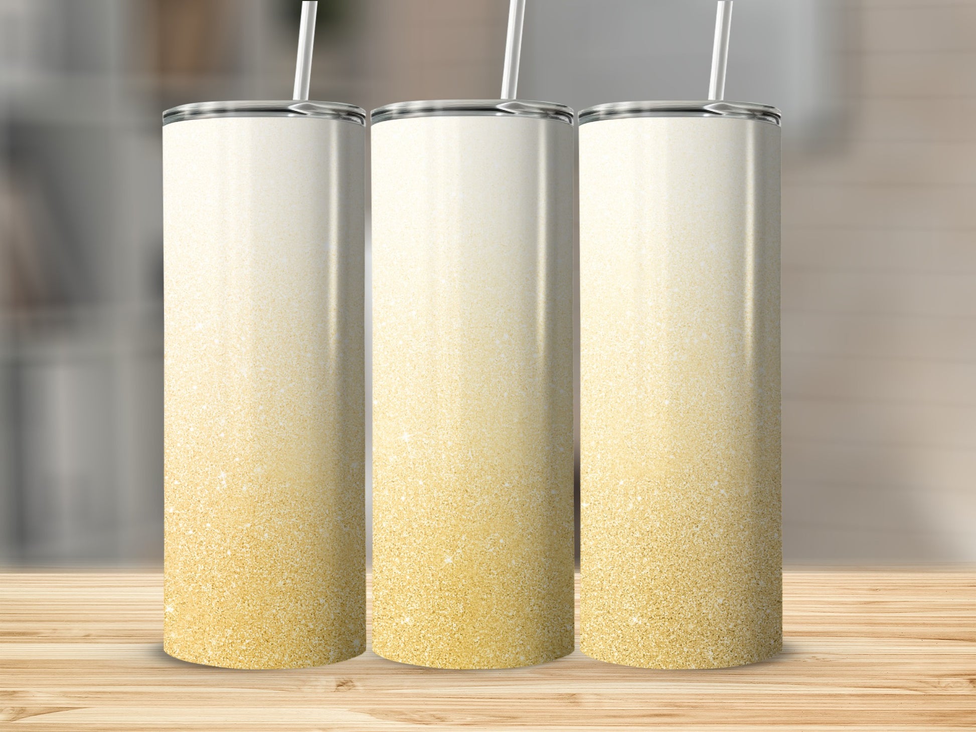 Three tall, ombre glitter tumblers with straws stand on a wooden surface.