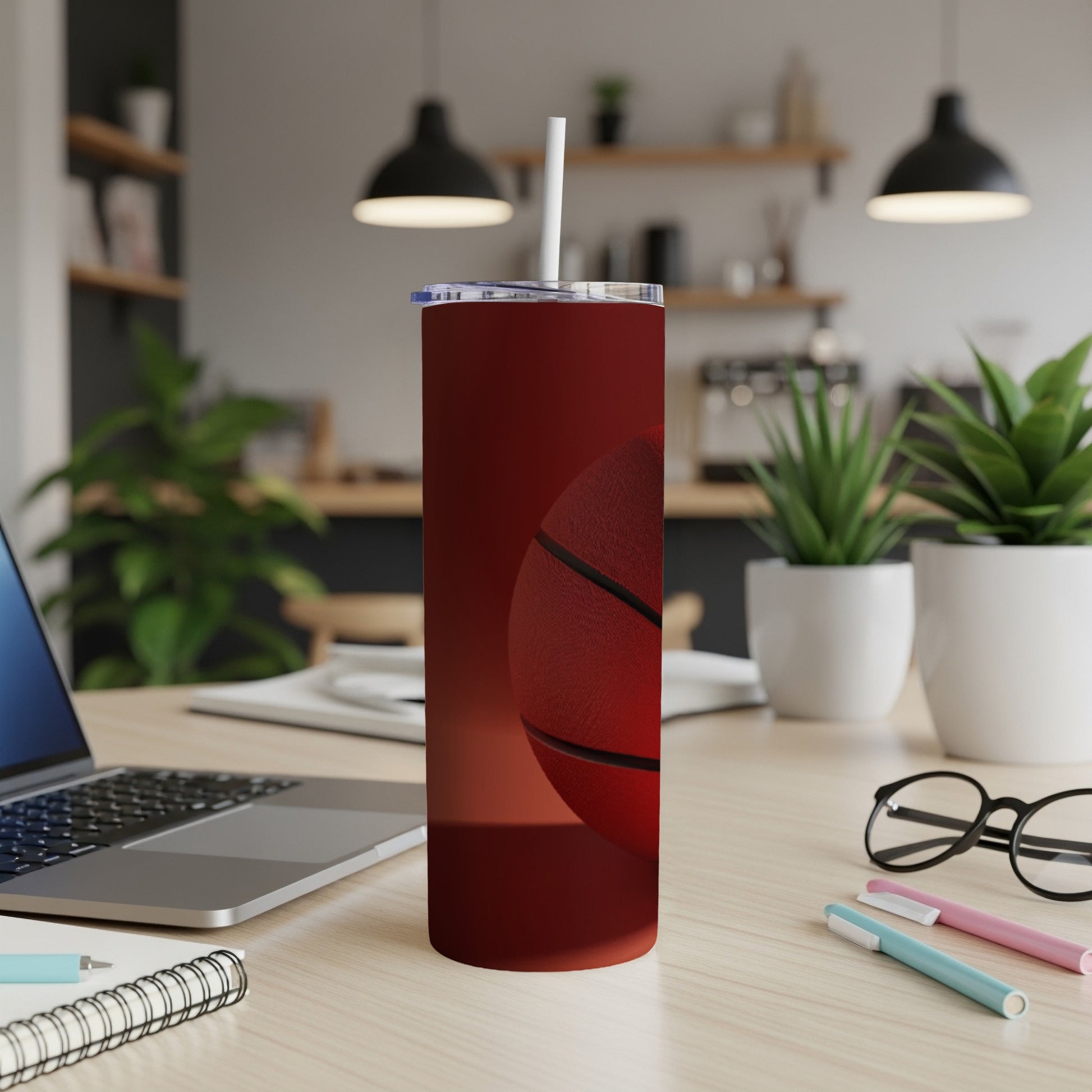 Red basketball tumbler with straw on a desk next to a laptop.
