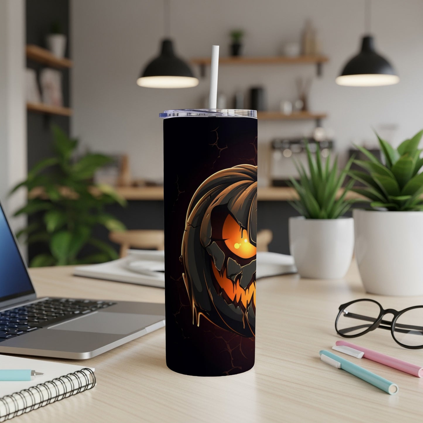 Tall black tumbler with a glowing jack-o'-lantern design and a straw.