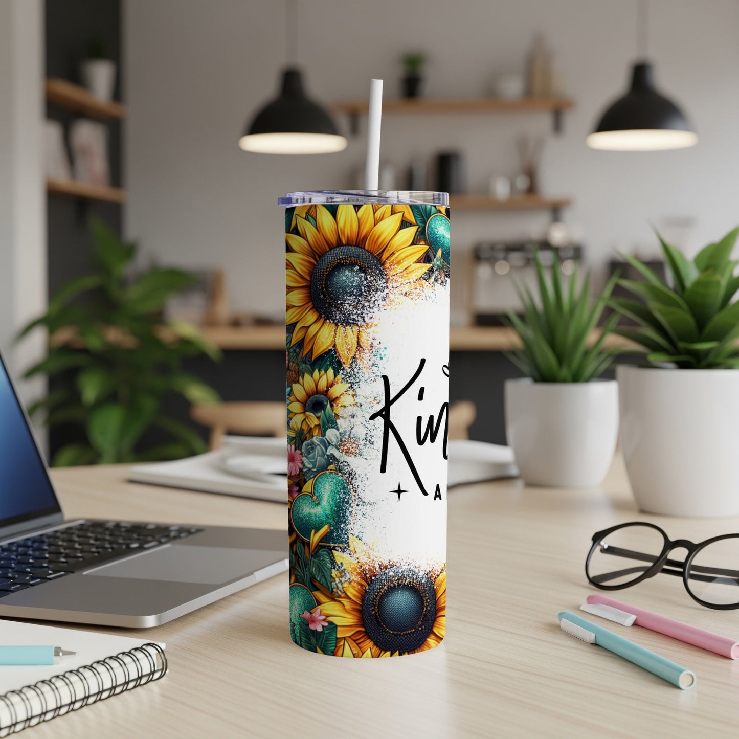 Tall tumbler with sunflowers and "Kindness" text on a desk.