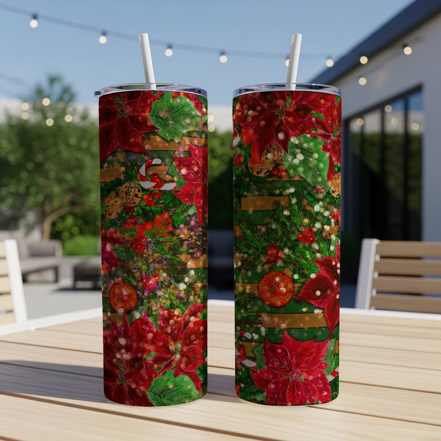 Two holiday-themed tumblers with poinsettias and pine branches on a wooden table.