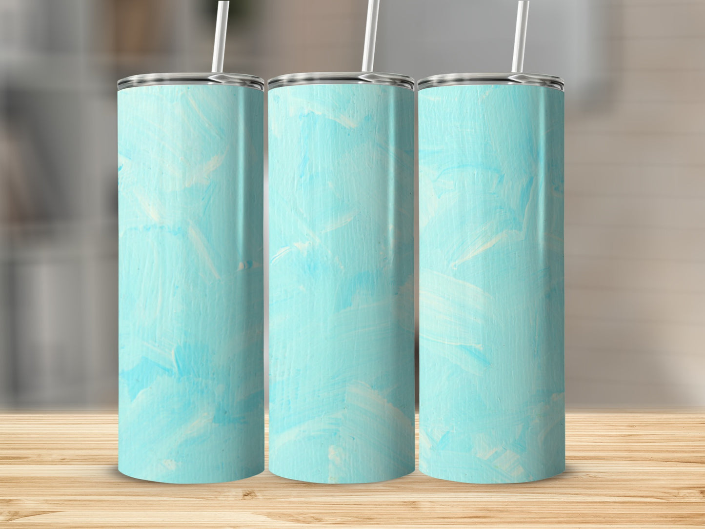 Three light blue textured tumblers with white straws, displayed on a wooden surface.