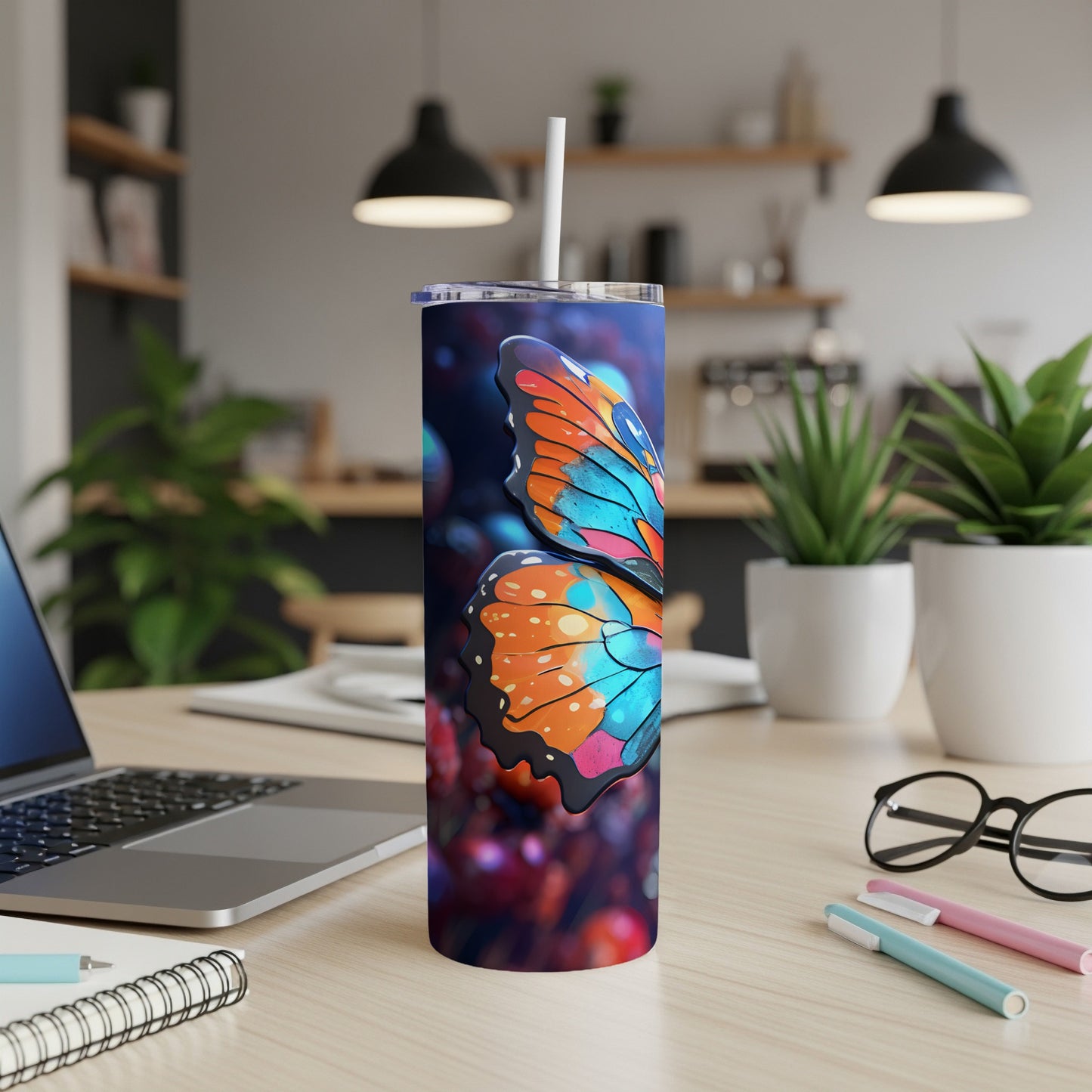 Tumbler with colorful butterfly wings and a straw on a desk.