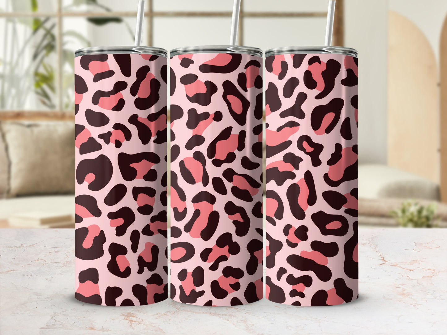 Three tumblers with a pink and brown leopard print pattern and silver straws.