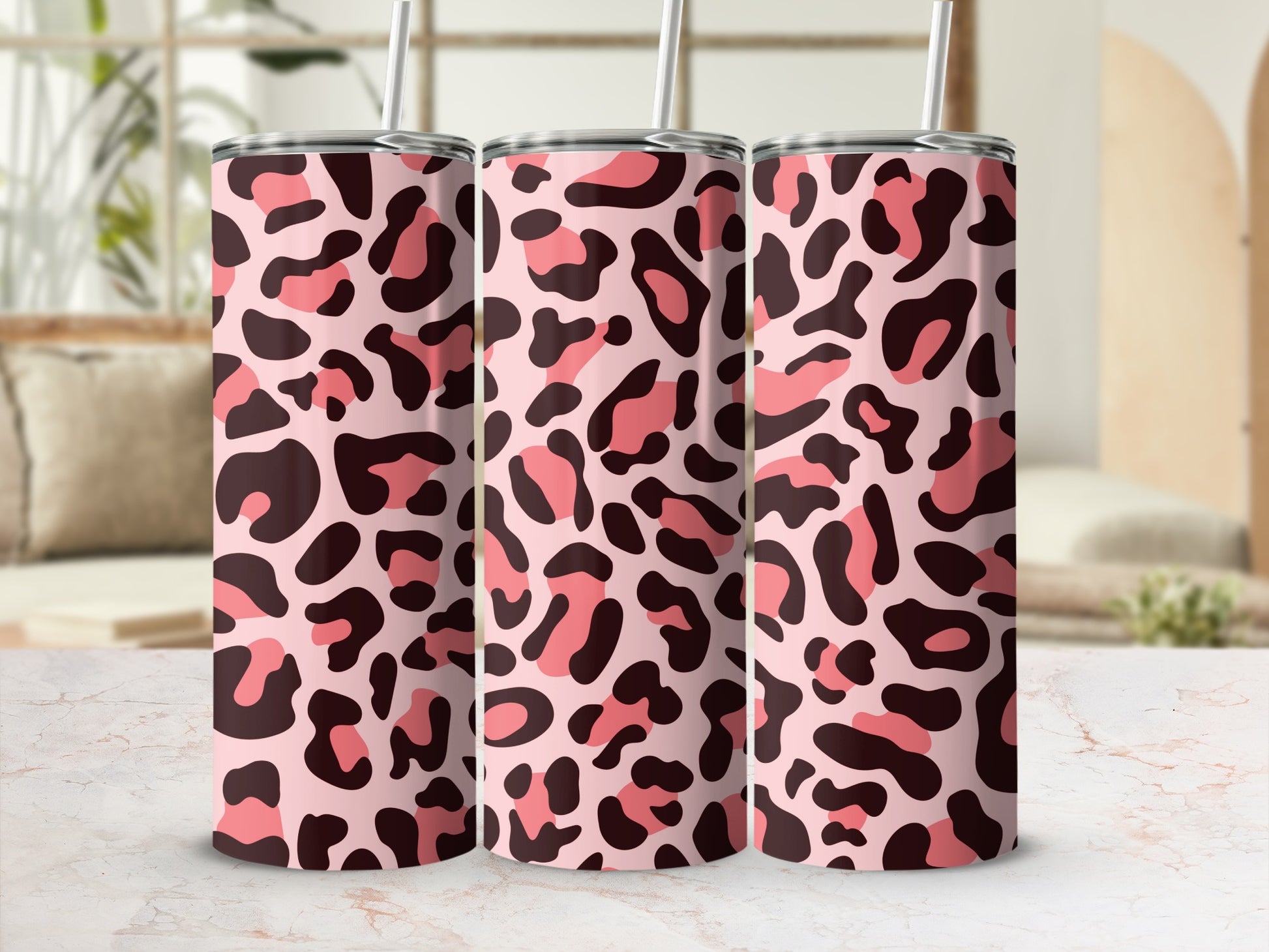 Three tumblers with a pink and brown leopard print pattern and silver straws.