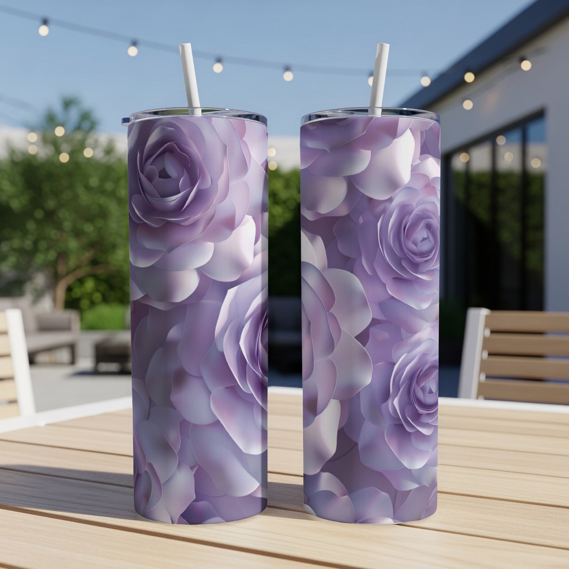 Two tall purple floral tumblers with straws on a wooden table outdoors.