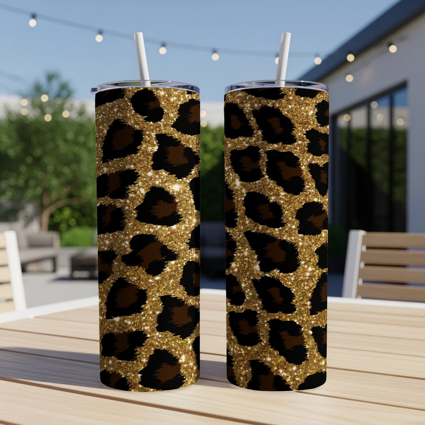 Two glittery gold leopard print tumblers with white straws on a wooden table.