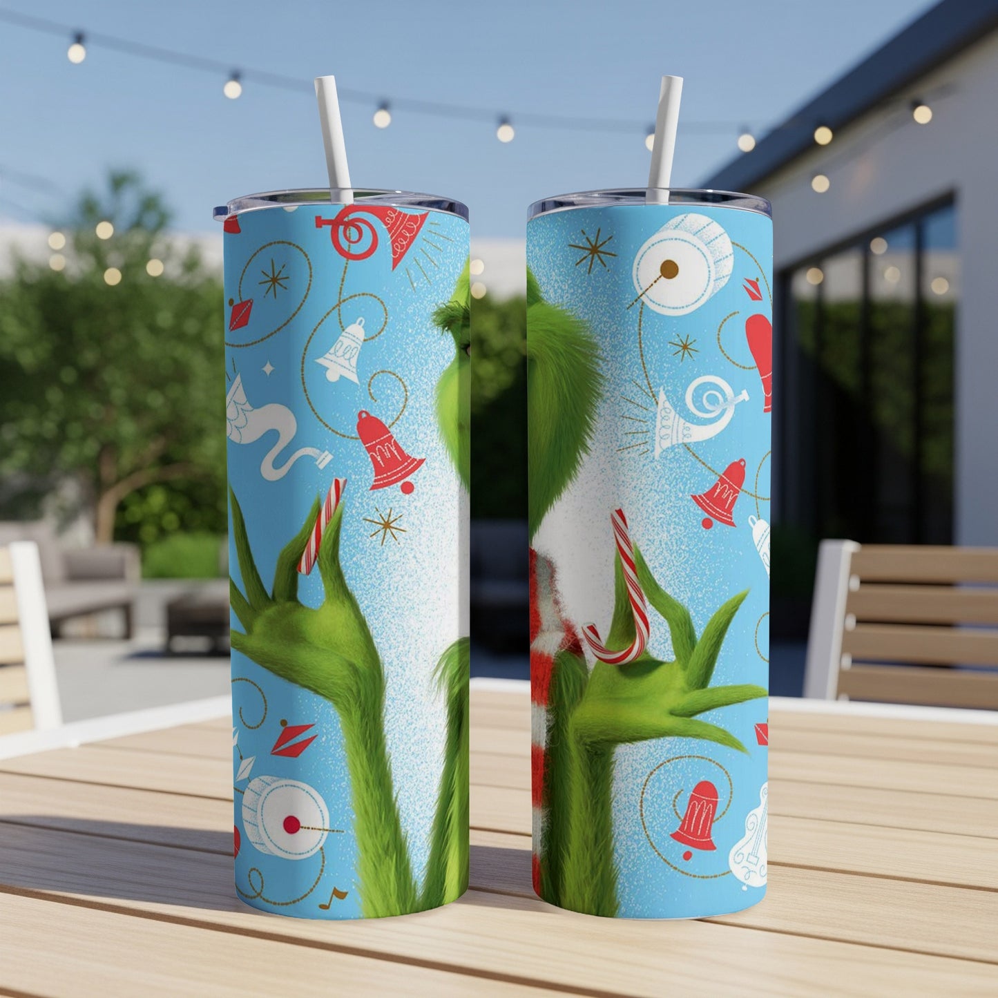 Two Grinch-themed tumblers with candy cane and bell icons on a table.