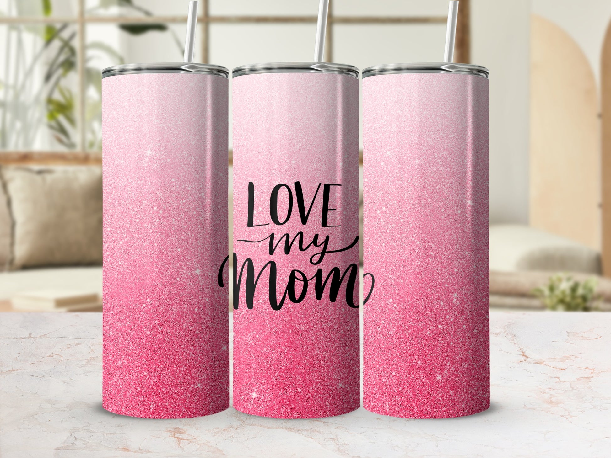 Pink glitter tumbler with "Love my mom" text on a marbled surface.