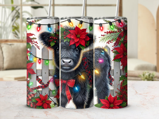 Christmas cow with festive lights and poinsettias on a tumbler.