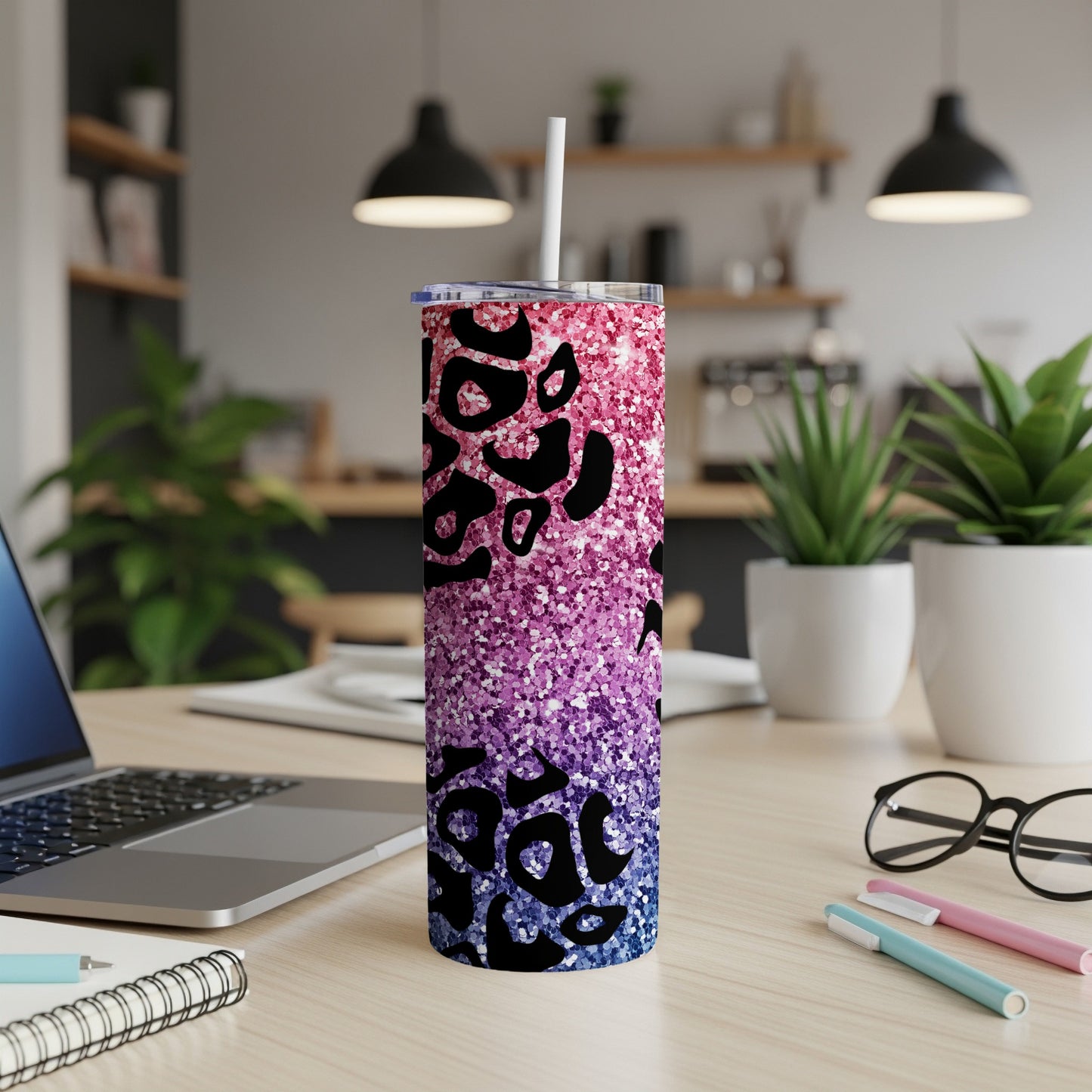 Glittering leopard print skinny tumbler with a white straw on a wooden desk.