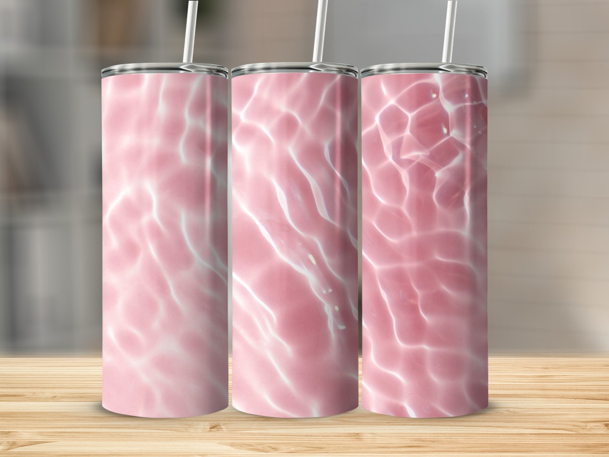 Three pink tumblers with water ripple design on wooden surface.