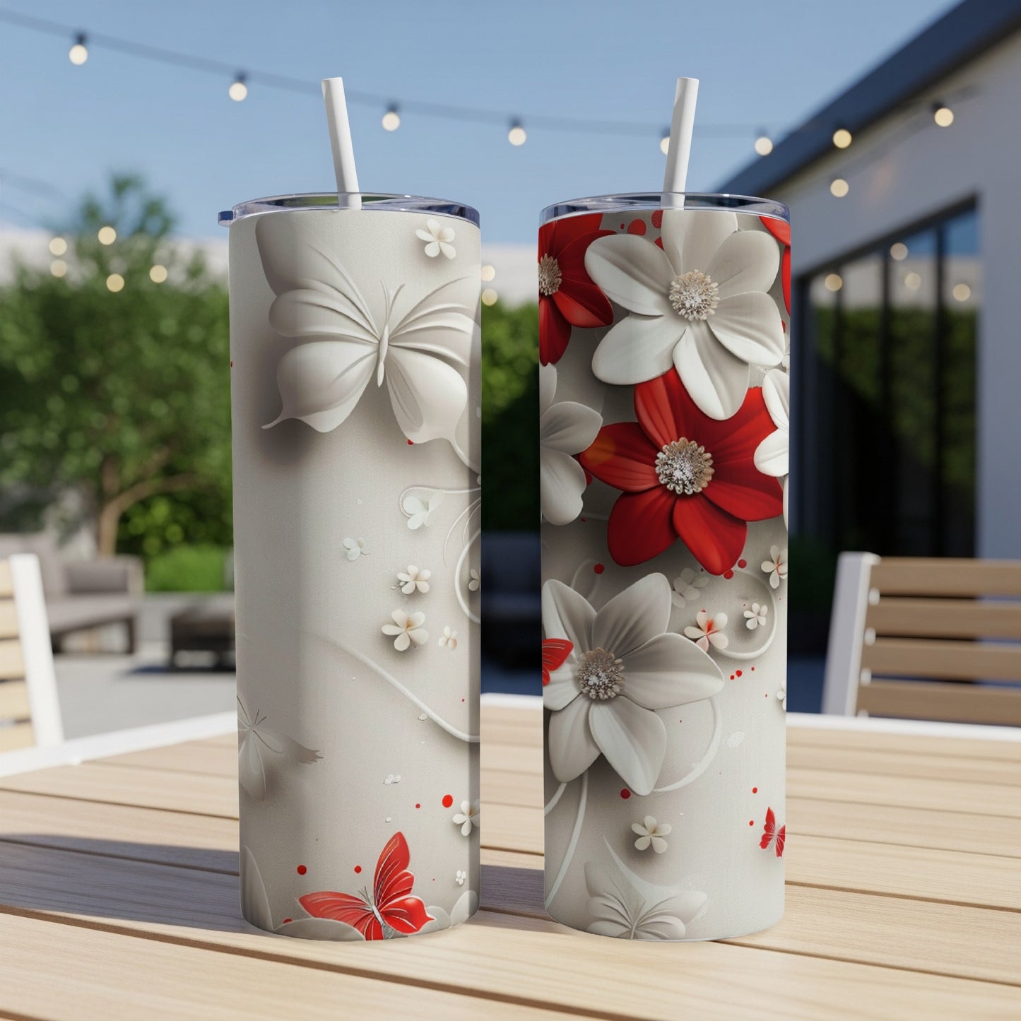 Two tall tumblers with white butterflies and floral designs on a patio table.