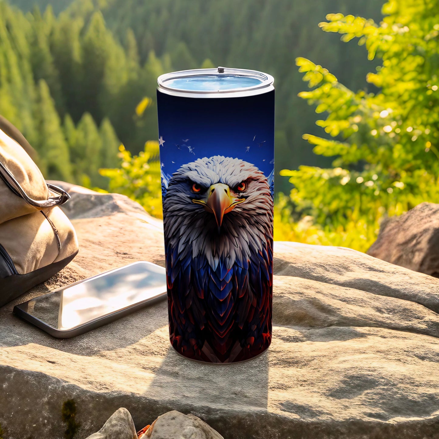 Stainless steel tumbler featuring a patriotic eagle design, on a rocky outdoor surface.