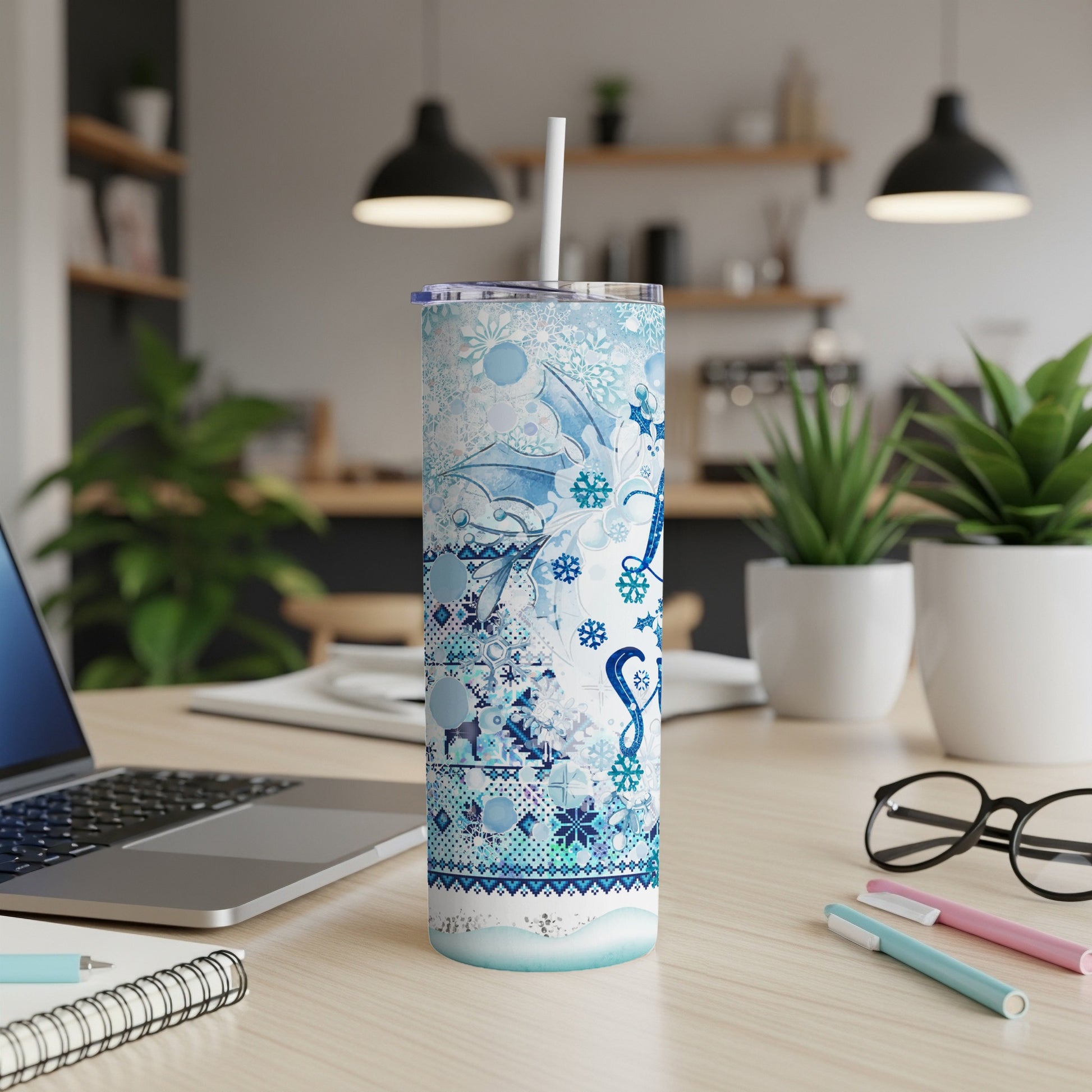Blue patterned skinny tumbler with lid and straw on a desk.