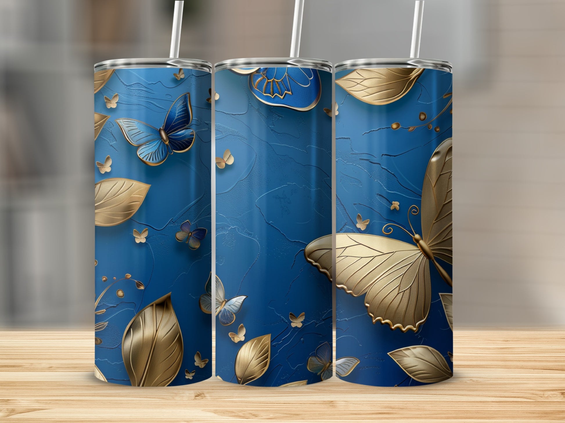 Blue tumbler with gold butterflies and leaves, on a wooden surface.