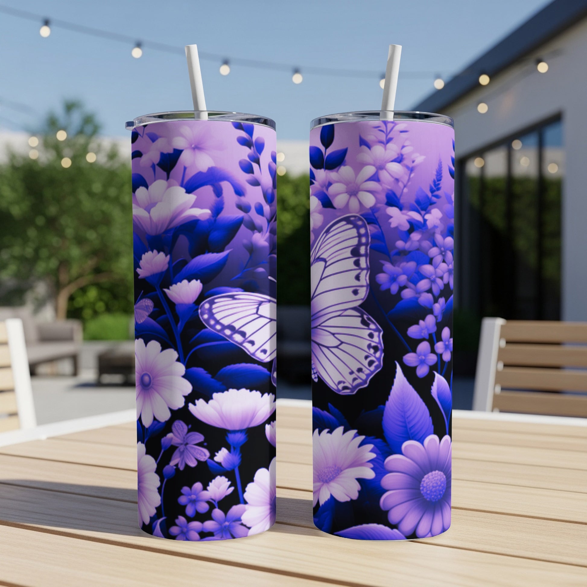 Two purple floral tumblers with a butterfly design on a table outdoors.