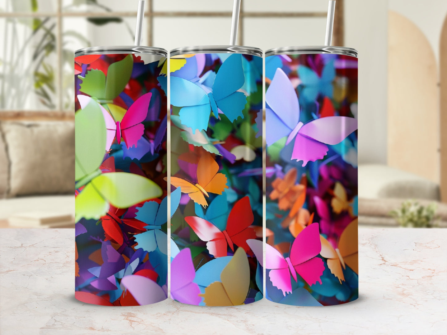 Three tumblers with colorful butterfly patterns on a speckled surface.