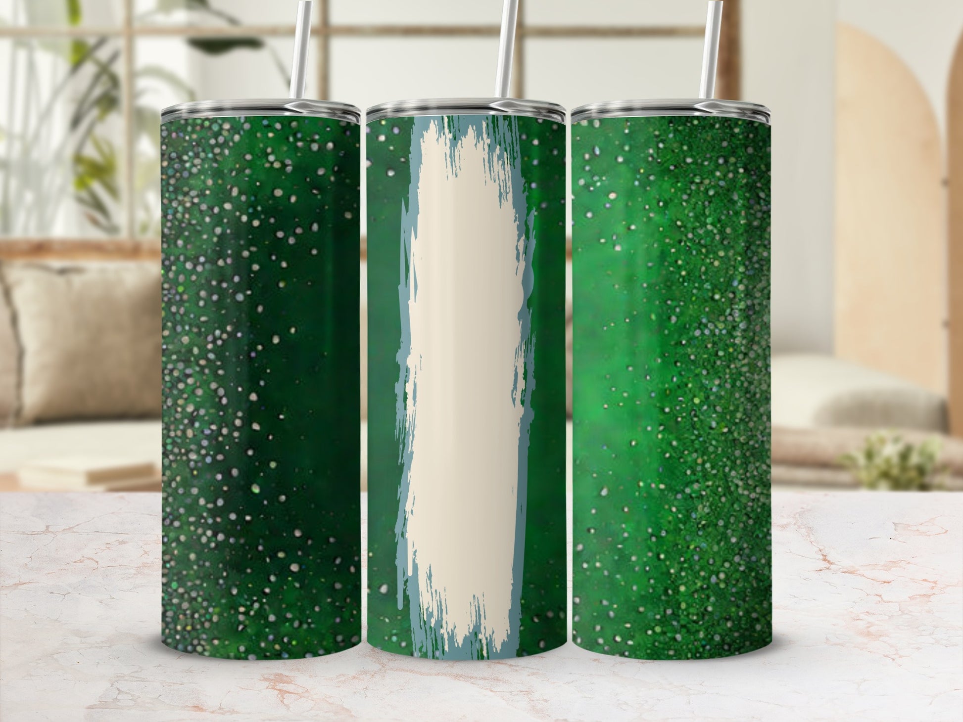 Three green speckled tumblers with straws on a marble surface.