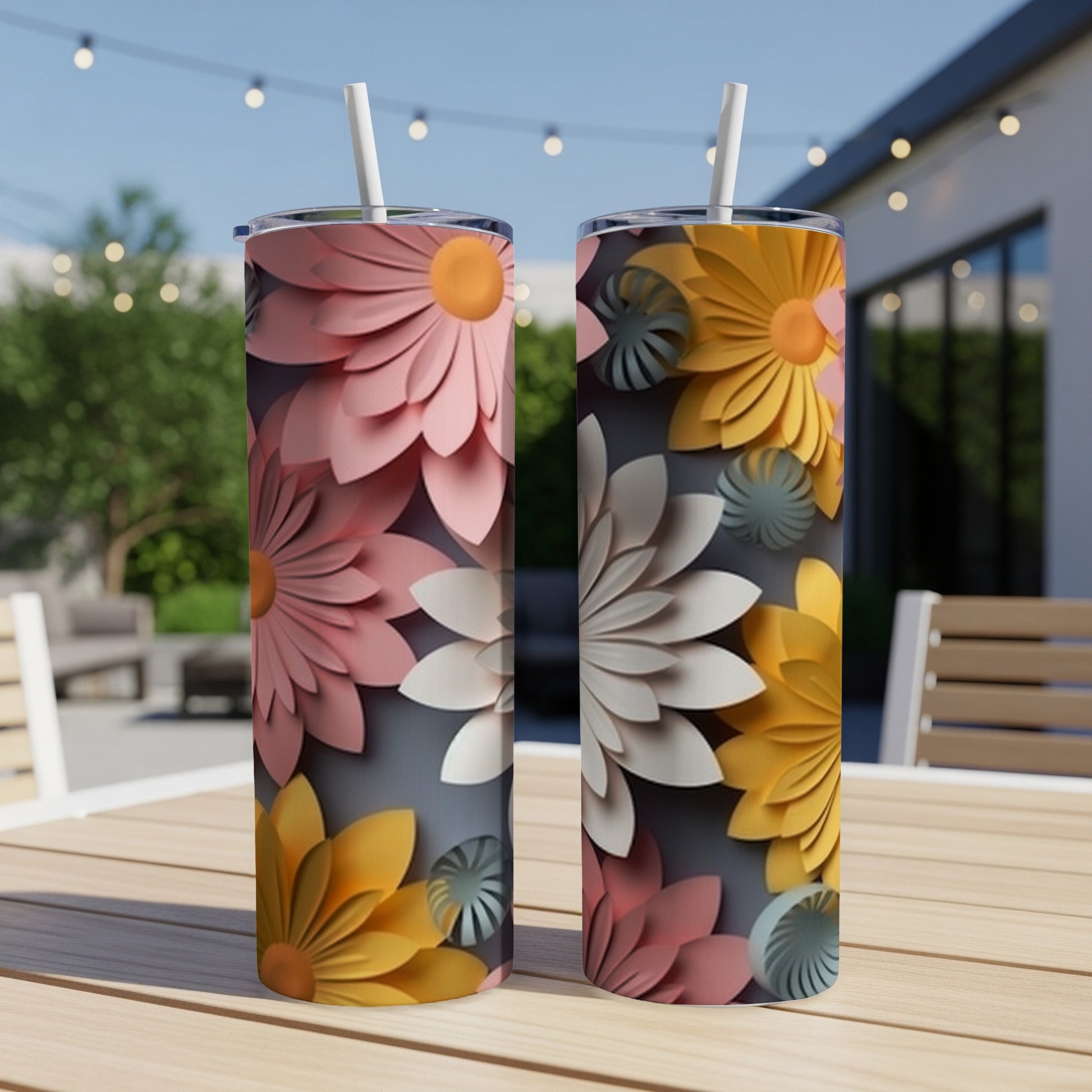 Two tumblers with colorful floral designs on a table outdoors.