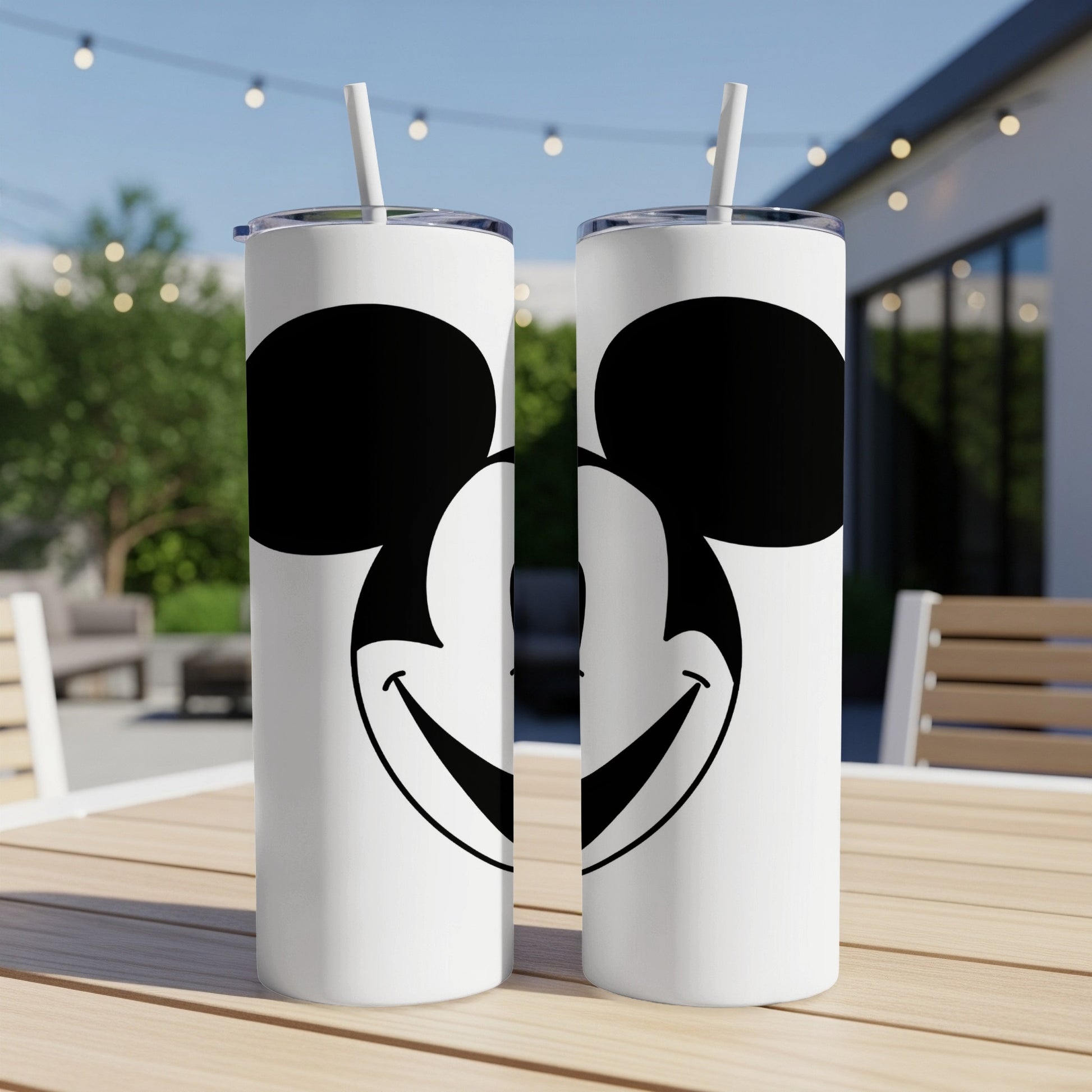 Two white tumblers with Mickey Mouse's face graphic and straws.